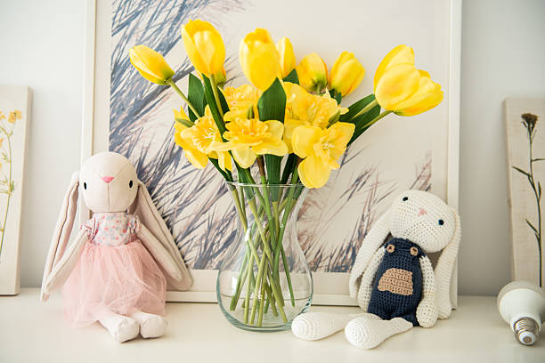 istock Plush bunnies next to a vase with yellow flower on a shelf decor for Easter 2209021362