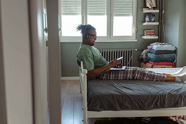 istock Man working from bed with laptop and smartphone in a cozy and bright room 2209021606