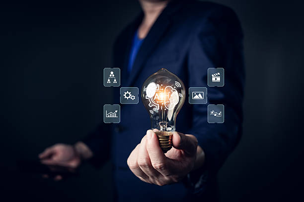 istock A person in a suit holds a glowing lightbulb featuring AI-related icons such as gears, graphs, and media, symbolizing innovation, creativity, and the ability to generate intelligent solutions. 2209026203