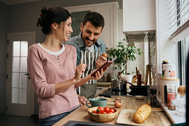 istock Happy couple using cell phone while cooking together in the kitchen. 2209029165