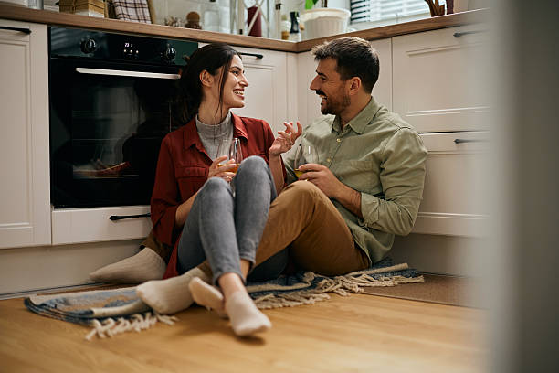 istock Happy couple talking while drinking wine and relaxing in the kitchen. 2209029333