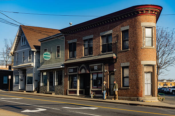 March 13, 2025 - Suffern, NY, USA On a sunny, but cold spring day the streets are nearly empty except for two men talking beside a brick building on a street corner.