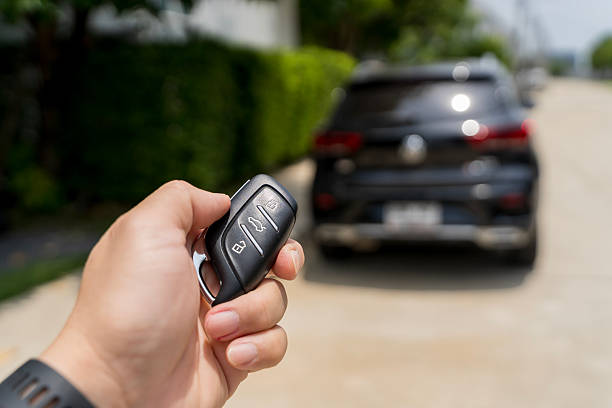 Car remote control by smart key, Hand holding smart key to lock doors of black car.