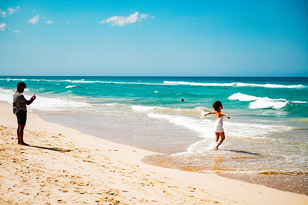 Young man photographing girlfriend on the beach