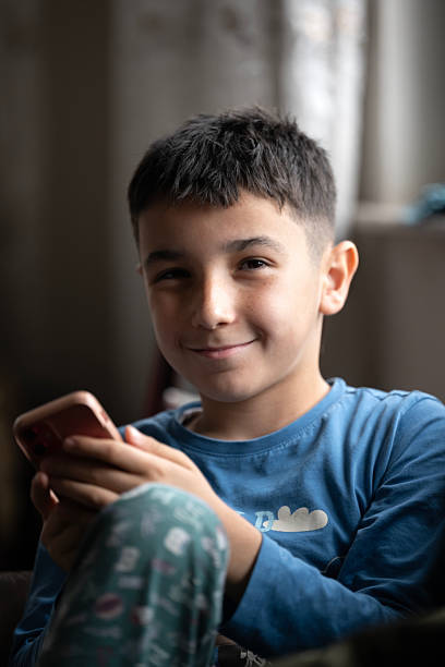 istock Preadolescent boy focused on watching content on smart phone at home 2209038721
