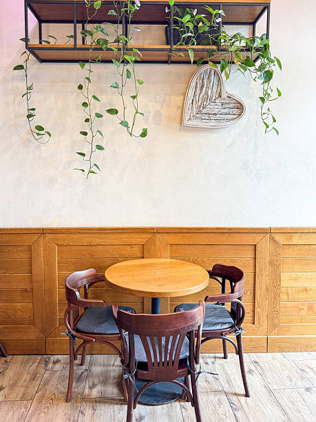 istock A cozy caf? corner features a round wooden table with four dark chairs beneath a wall shelf of trailing plants 2209039020