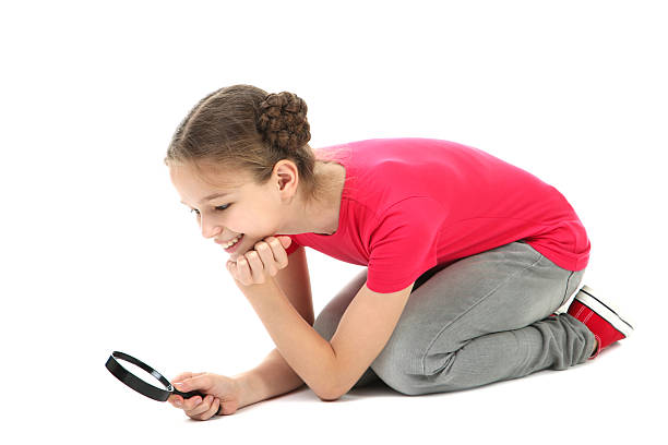 istock Cute young girl with magnifying glass on white background 2209042892