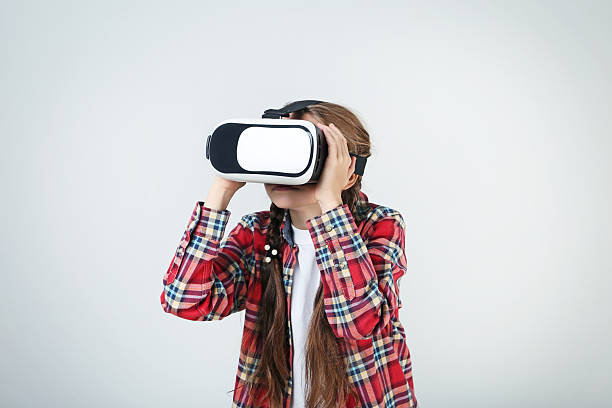istock Young girl in virtual reality goggles on grey background 2209044240