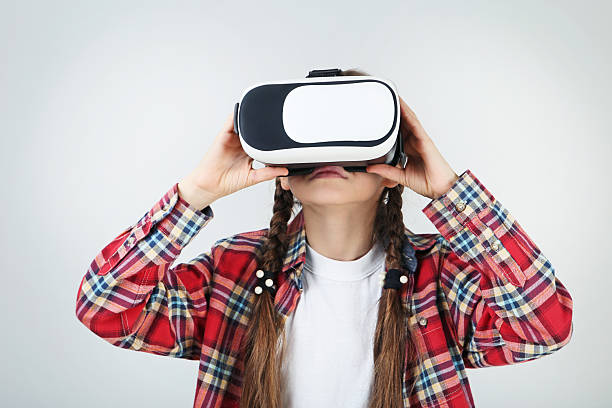 istock Young girl in virtual reality goggles on grey background 2209044589