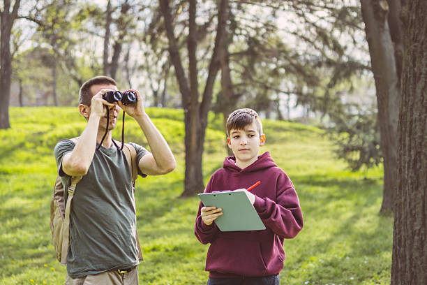 istock Father and son bonding thorough the same outdoor hobby. They are spending their free weekends at national park to watch and explore birds, insects and plants. 2209044689