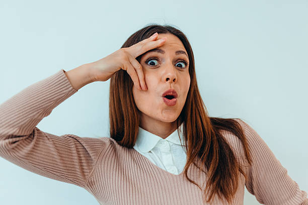 Shocked young woman in casual clothes with her mouth open after hearing a surprise. Surprised woman receiving good or bad news while posing in front of a white background