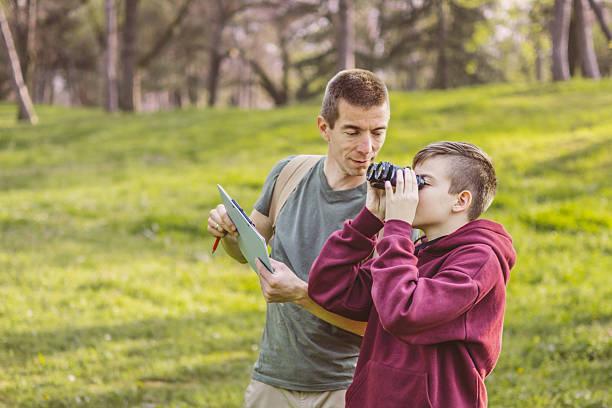 istock Father and son bonding thorough the same outdoor hobby. They are spending their free weekends at national park to watch and explore birds, insects and plants. 2209045237