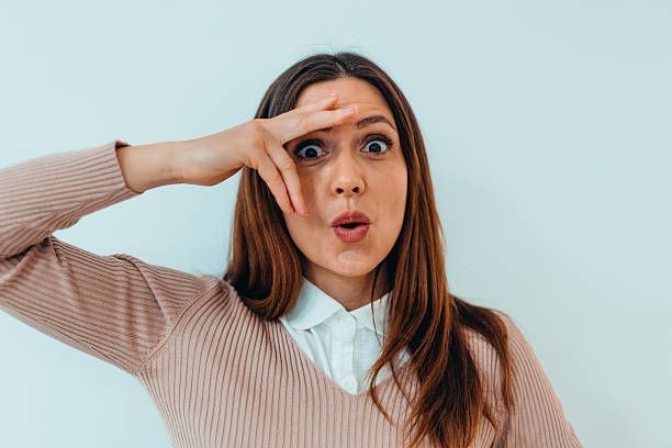 istock Surprised Woman Expressing Excitement with Gestures Against Light Background 2209045297