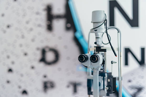 Optical equipment used for eye examinations positioned in front of a blurred vision test chart, representing modern technology in healthcare and vision care. Ideal for topics on ophthalmology, optometry, and medical technology.