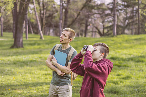 istock Father and son bonding thorough the same outdoor hobby. They are spending their free weekends at national park to watch and explore birds, insects and plants. 2209045441