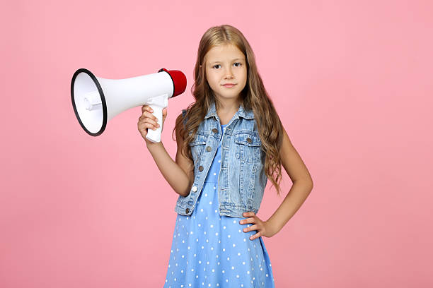 istock Beautiful little girl with megaphone on pink background 2209045574