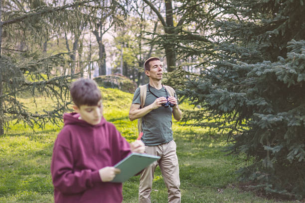 istock Father and son bonding thorough the same outdoor hobby. They are spending their free weekends at national park to watch and explore birds, insects and plants. 2209045768