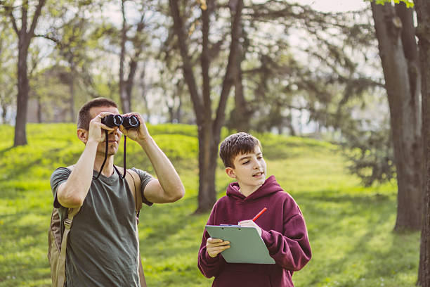 istock Father and son bonding thorough the same outdoor hobby. They are spending their free weekends at national park to watch and explore birds, insects and plants. 2209045886