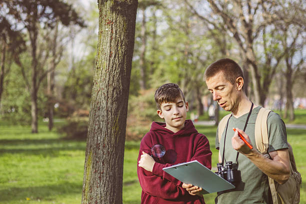 istock Father and son bonding thorough the same outdoor hobby. They are spending their free weekends at national park to watch and explore birds, insects and plants. 2209046572