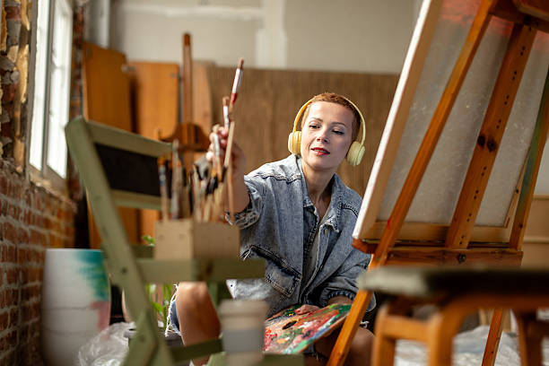 istock Engaging in creative expression, a young adult artist works in a vibrant indoor studio while listening to music 2209047241