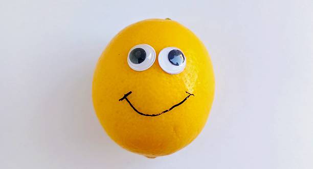 istock One yellow lemon on a white background with funny plastic eyes on the lemon 2209049196