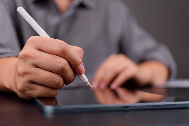 istock Close-up of hand using stylus on digital tablet, representing e-signature, paperless workflow, and modern business documentation. 2209049298