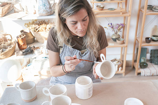 istock Overhead View of Ceramicist Glazing Handmade Mugs 2209051887