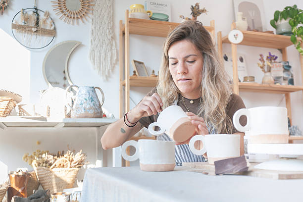 istock Female Ceramicist Decorating Mug Collection at Workbench 2209051997