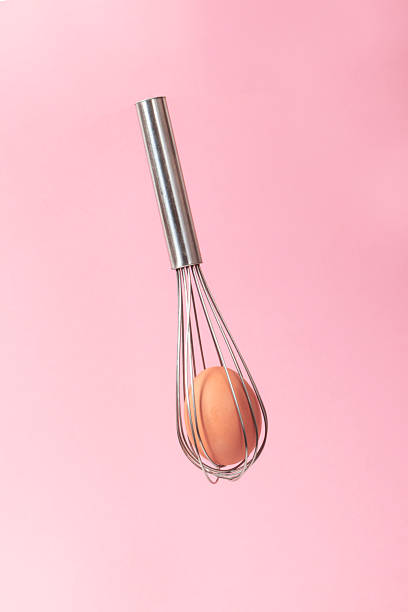 istock a pastry whisk with a fresh egg inside, levitating on a pink background 2209053210