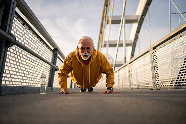 istock Senior man doing push-ups on a bridge during his outdoor workout 2209053212