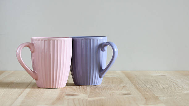 istock Two colorful coffee mugs sitting on wooden table 2209057029