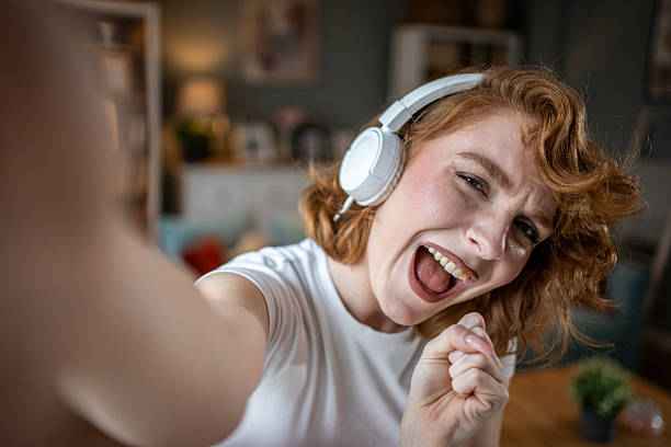 istock Young woman singing and taking a selfie while wearing headphones 2209058042