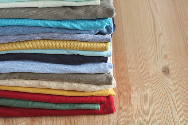 istock Stack of folded colorful t-shirts lying on wooden table 2209058442