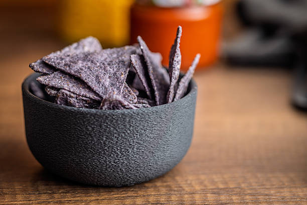 istock Dark nachos chips in bowl on wooden table. 2209063922