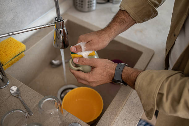 istock Man washing dishes in kitchen sink with sponge 2209071025