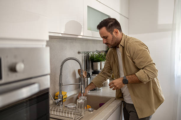 istock Man washing dishes in modern kitchen sink 2209071026