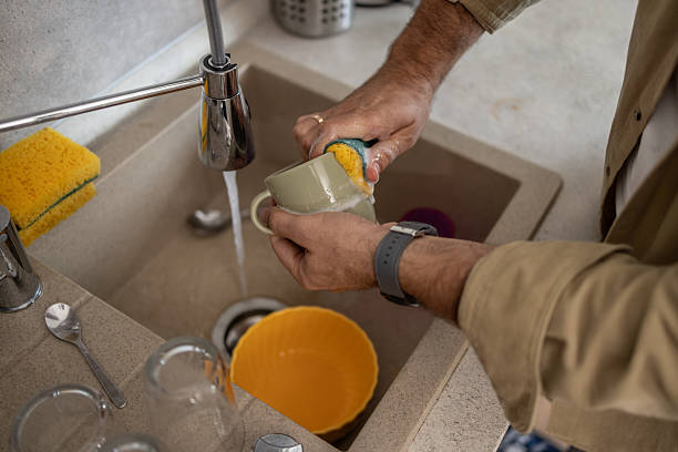 istock Man washing dishes in kitchen sink with sponge 2209071029