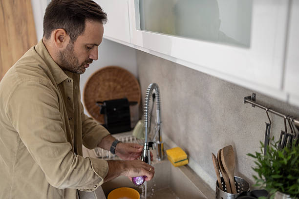 istock Man washing an onion in the kitchen sink 2209071050