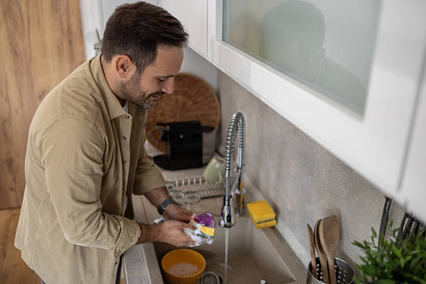 istock Man washing dishes in modern kitchen sink with sponge 2209071051