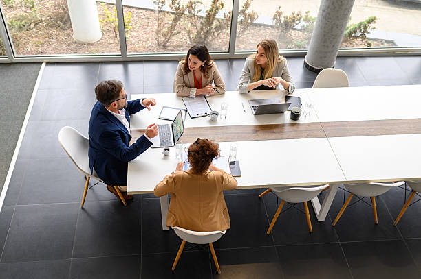 istock High angle view of business professionals with technologies and documents reviewing project details in board room 2209071223