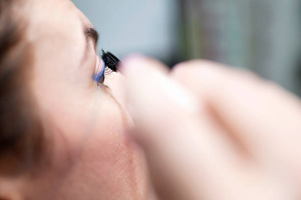 Close up shot of young woman doing a daily make-up routine in front of a mirror at her home bathroom before getting ready for going out