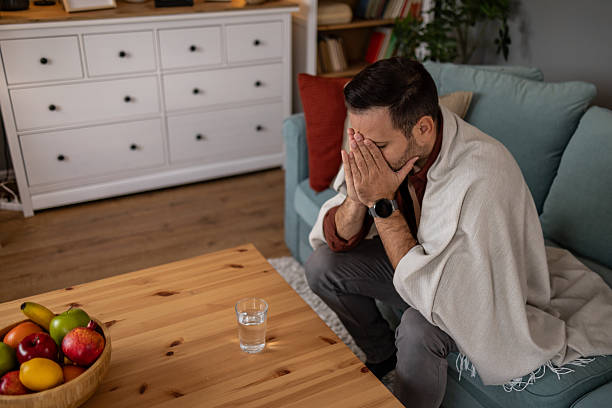 istock Sick man sitting on sofa covering his face with hands 2209073244