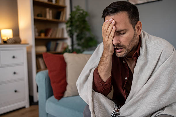 istock Sick man suffering from headache wrapped in blanket at home 2209073312