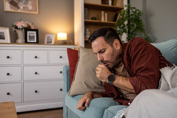 istock Sick man coughing on sofa at home 2209073322