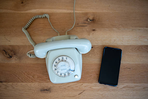 Vintage rotary phone and modern smartphone on wooden surface comparison. stock photo