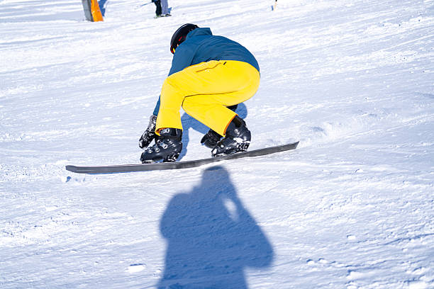 Snowboarder carving snowy slope reflected in ski goggles with water drops, pine forest under clear winter sky, concept extreme sport, safety, perspective.