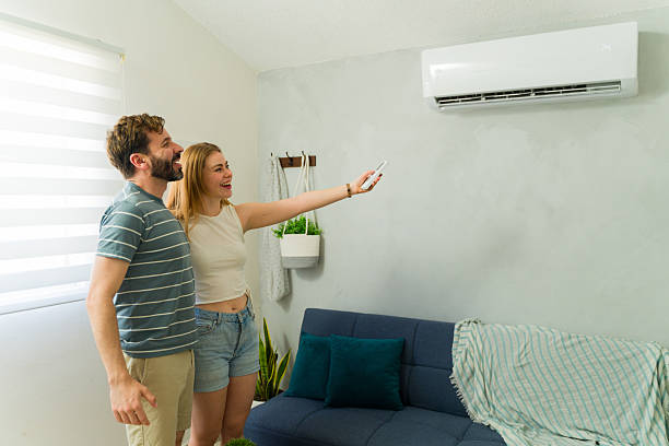 istock Happy couple turning on air conditioning unit at home during summer 2209076966