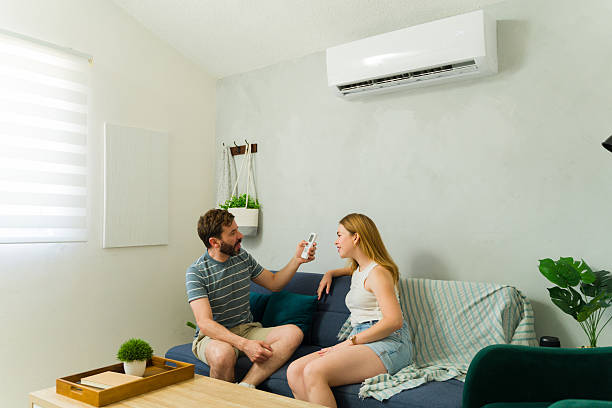 istock Couple relaxing on sofa using air conditioner remote control in living room 2209077009