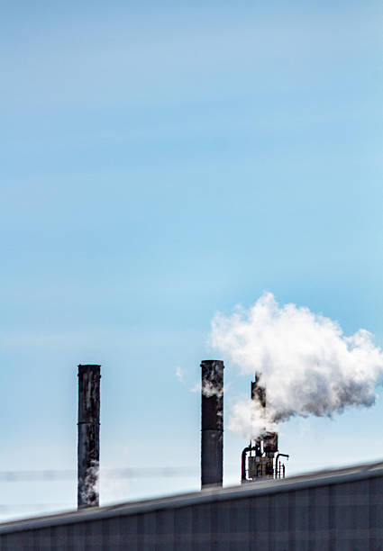 istock Industrial Chimneys Emitting Smoke with Blue Sky in Background 2209077035