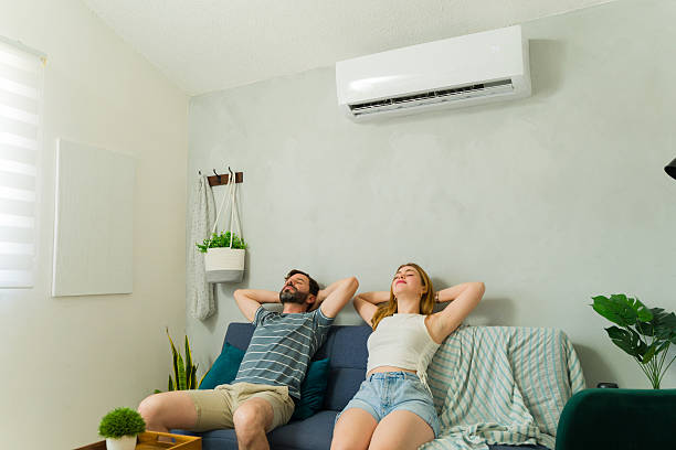 istock Couple relaxing on sofa under air conditioning unit at home 2209077051